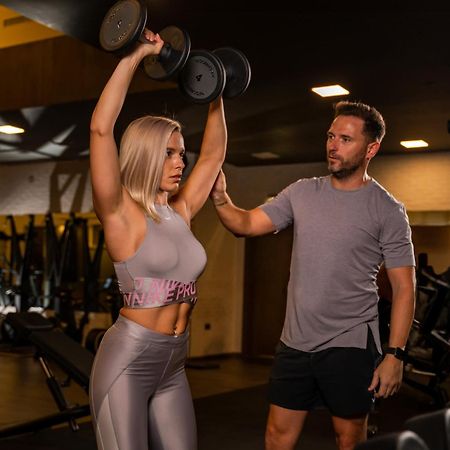 Five Jumeirah Village ดูไบ ภายนอก รูปภาพ Personal trainer assisting a woman with a dumbbell press