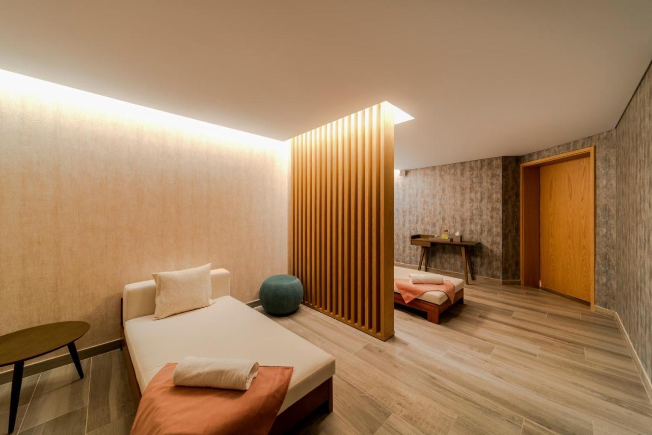 Five Jumeirah Village ดูไบ ภายนอก รูปภาพ The photo depicts a calm and modern interior space, likely a relaxation or wellness area. It features a light-colored wood floor and soothing wall textures. 

On one side, there’s a daybed with soft cushions, accompanied by a small round table. A blu